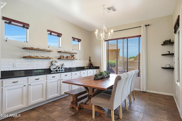 dining room featuring dark tile patterned floors, a notable chandelier, and plenty of natural light