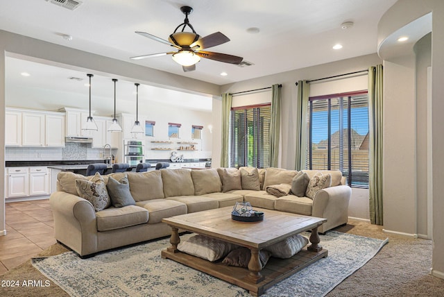 living room featuring light tile patterned flooring, ceiling fan, and sink