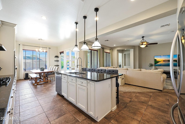 kitchen featuring pendant lighting, a center island with sink, white cabinetry, appliances with stainless steel finishes, and sink