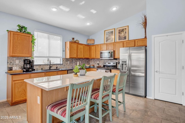 kitchen with a sink, backsplash, a breakfast bar, and stainless steel appliances