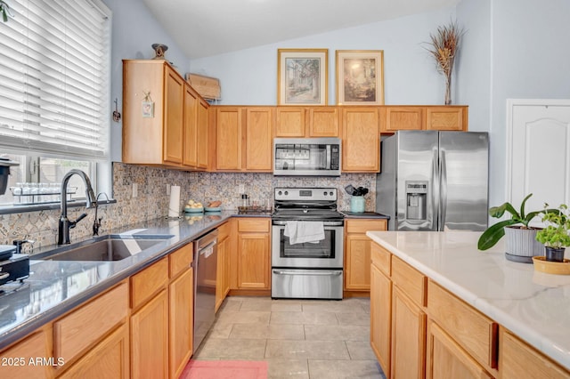 kitchen featuring light tile patterned flooring, a sink, stainless steel appliances, backsplash, and vaulted ceiling