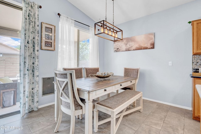 dining space with baseboards, a notable chandelier, light tile patterned floors, and lofted ceiling
