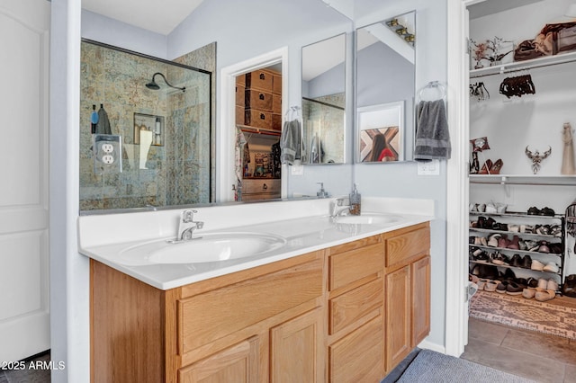 bathroom with tile patterned flooring, a sink, a walk in closet, and a shower stall