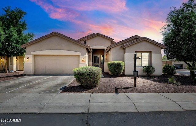 single story home with an attached garage, driveway, a tile roof, and stucco siding