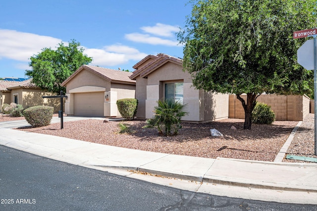 view of front of house featuring driveway, a tile roof, fence, an attached garage, and stucco siding