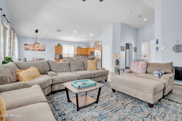 living room featuring visible vents, arched walkways, recessed lighting, and high vaulted ceiling