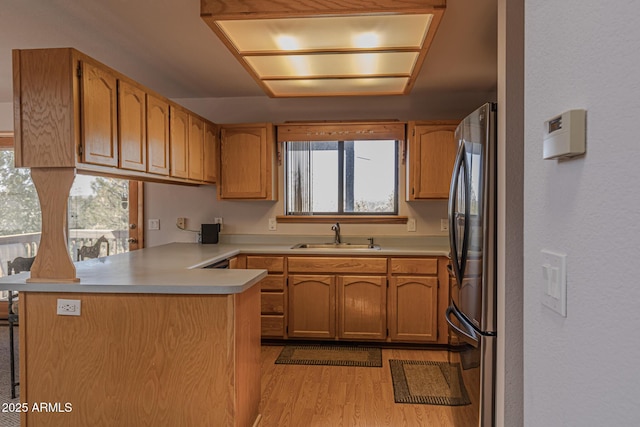 2806 Skyhawk Dr, Overgaard, AZ 85933 - kitchen with a peninsula, freestanding refrigerator, a sink, light wood-style floors, and light countertops