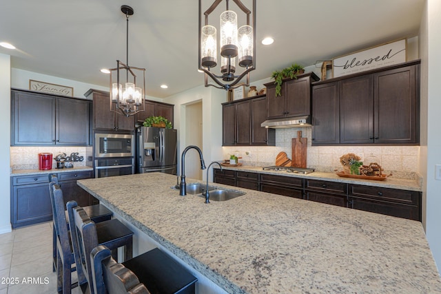 kitchen with hanging light fixtures, appliances with stainless steel finishes, sink, and dark brown cabinets