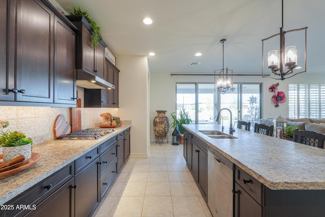 kitchen with appliances with stainless steel finishes, an island with sink, sink, a chandelier, and hanging light fixtures