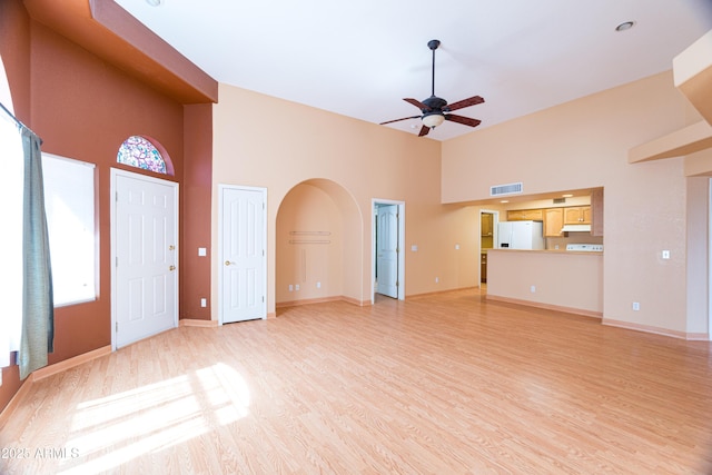 4484 Desert Springs Trl, Sierra Vista, AZ 85635 - unfurnished living room with a high ceiling, a ceiling fan, light wood-type flooring, arched walkways, and baseboards