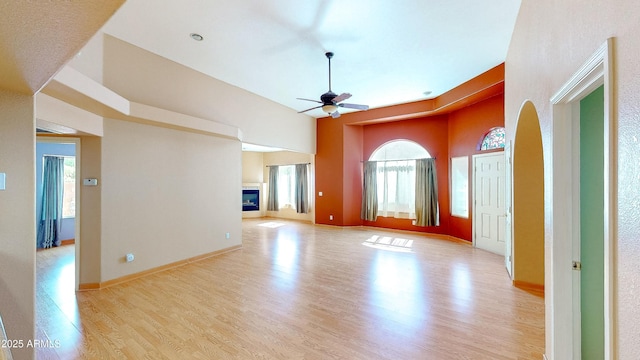 4484 Desert Springs Trl, Sierra Vista, AZ 85635 - unfurnished room with a ceiling fan, light wood-type flooring, a glass covered fireplace, a high ceiling, and baseboards
