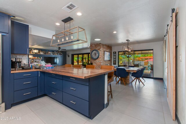 7102 E Kalil Dr, Scottsdale, AZ 85254 - kitchen featuring wooden counters, blue cabinets, a peninsula, plenty of natural light, and recessed lighting