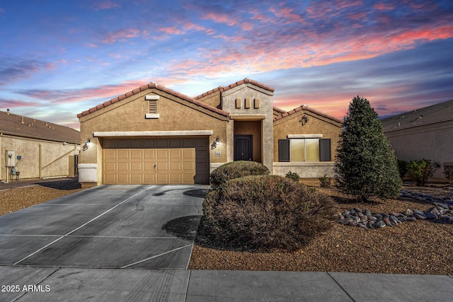 mediterranean / spanish-style house with a garage, a tile roof, driveway, and stucco siding