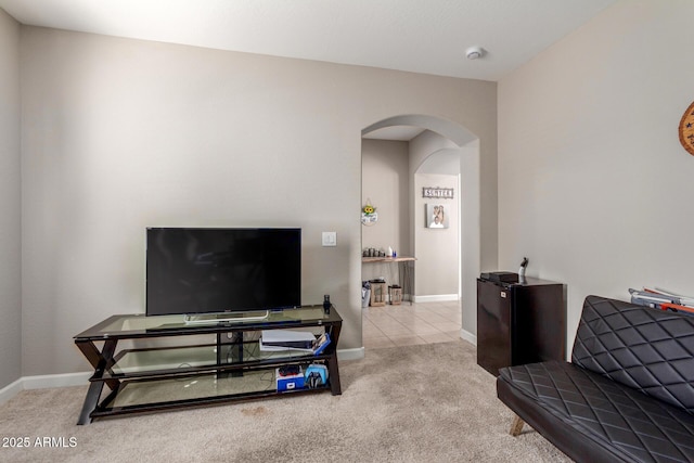 carpeted living room with baseboards and arched walkways