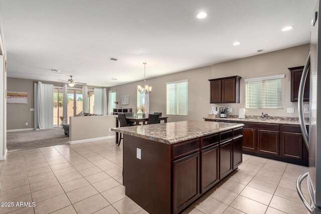 kitchen featuring light tile patterned floors, visible vents, open floor plan, and dark brown cabinets