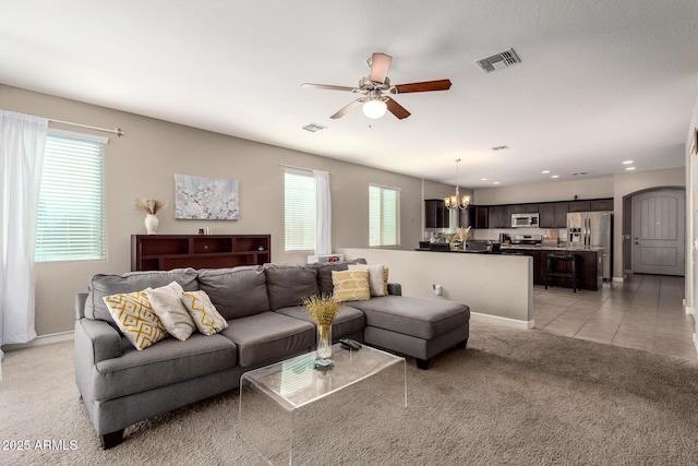 living room with light carpet, plenty of natural light, visible vents, and ceiling fan with notable chandelier