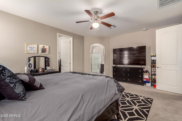 carpeted bedroom featuring connected bathroom, visible vents, arched walkways, and a ceiling fan