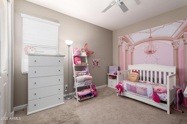 bedroom with a crib, ceiling fan, baseboards, and carpet flooring