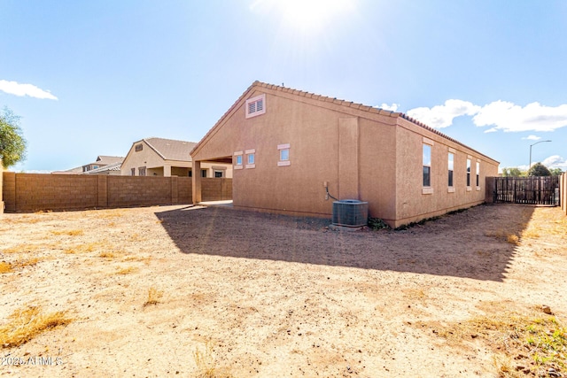 view of side of property featuring central air condition unit, a fenced backyard, and stucco siding