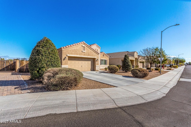 view of front of home with a garage, fence, driveway, a tiled roof, and stucco siding