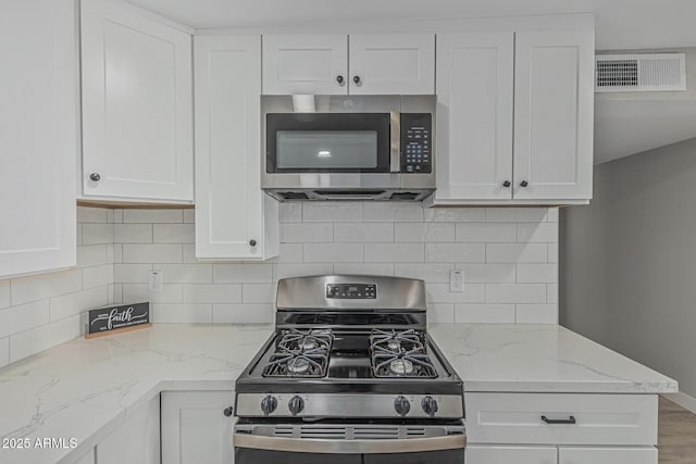 4441 N 27th Dr, Phoenix, AZ 85017 - kitchen featuring stainless steel appliances, white cabinets, light stone countertops, and tasteful backsplash