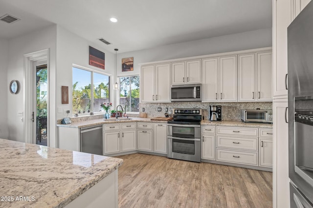 kitchen featuring white cabinetry, sink, light stone counters, light hardwood / wood-style floors, and stainless steel appliances