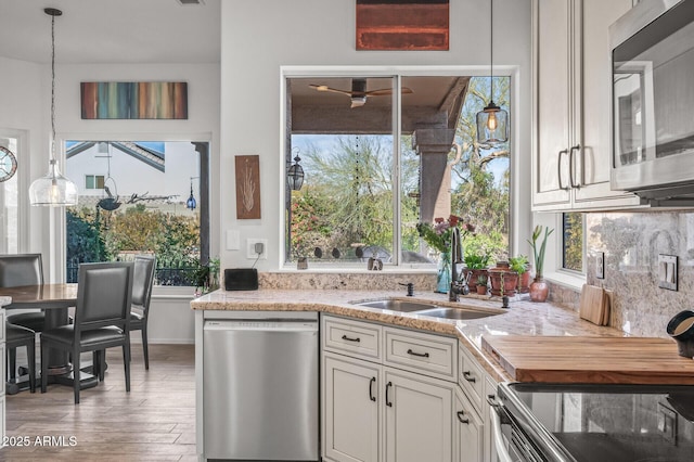 kitchen with stainless steel appliances, light hardwood / wood-style floors, sink, and light stone countertops