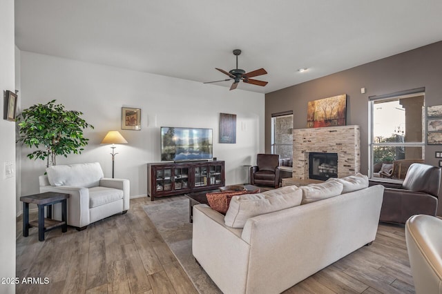 living room with ceiling fan, a fireplace, and light wood-type flooring