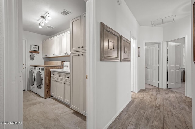 laundry room featuring cabinets, washing machine and dryer, and light hardwood / wood-style flooring