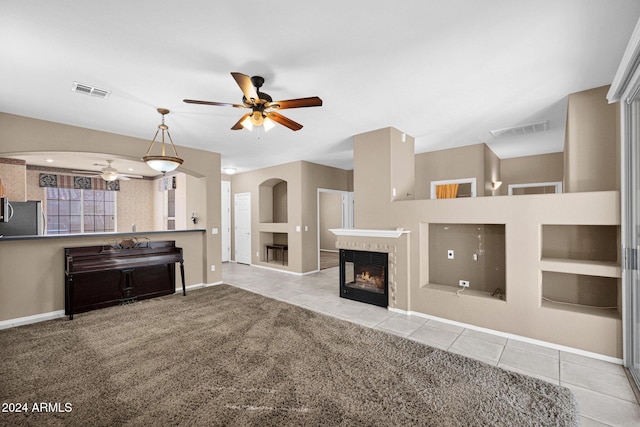 unfurnished living room featuring built in shelves, ceiling fan, a fireplace, and light tile patterned floors