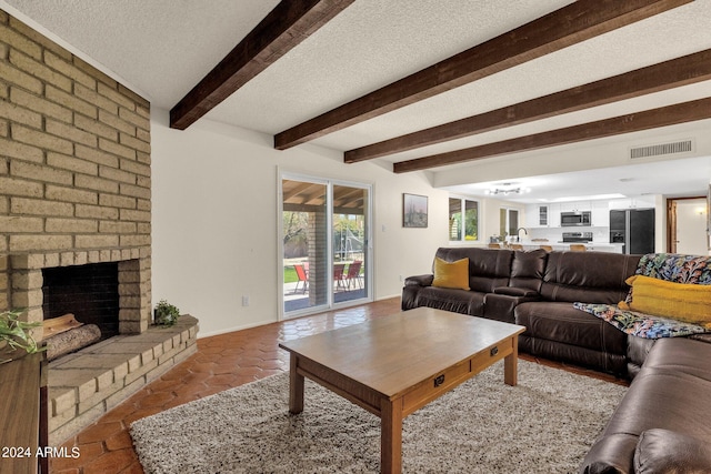 living room featuring a brick fireplace, beam ceiling, and a textured ceiling