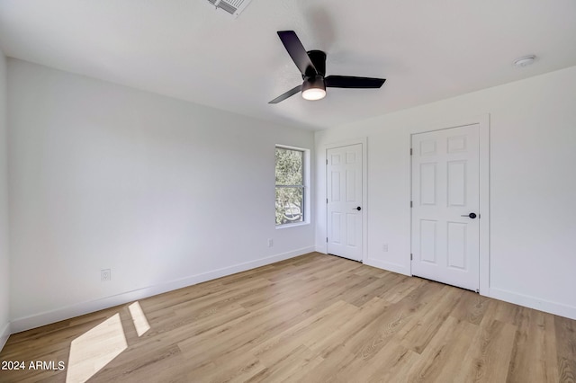 unfurnished bedroom with two closets, light hardwood / wood-style flooring, and ceiling fan