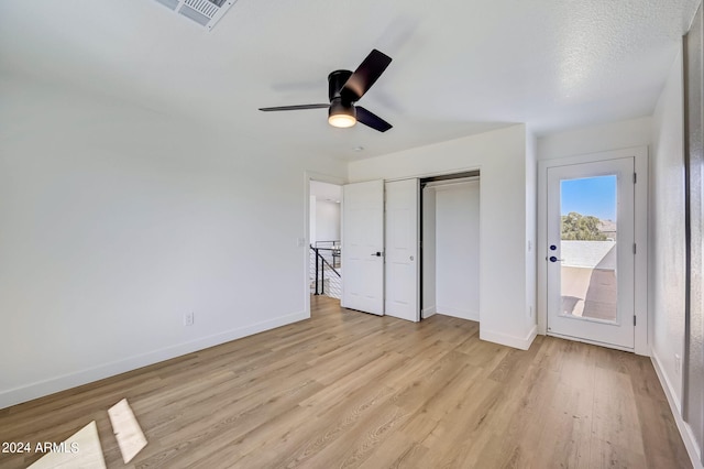 unfurnished bedroom featuring ceiling fan, light hardwood / wood-style floors, a textured ceiling, and a closet