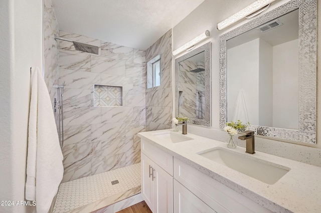 bathroom with a tile shower, vanity, a textured ceiling, and hardwood / wood-style floors