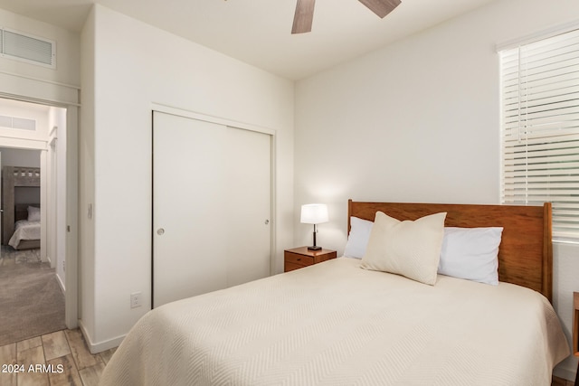 bedroom with light wood-type flooring, a closet, and ceiling fan