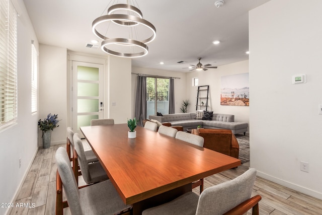 dining room with ceiling fan with notable chandelier and light wood-type flooring