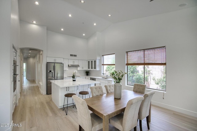 7214 E Rustling Pass, Scottsdale, AZ 85255 - dining room featuring high vaulted ceiling, arched walkways, baseboards, light wood finished floors, and recessed lighting