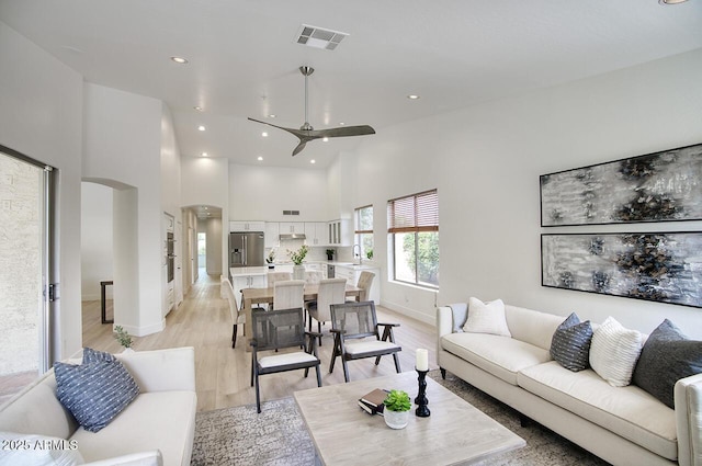 7214 E Rustling Pass, Scottsdale, AZ 85255 - living room with arched walkways, ceiling fan, light wood-type flooring, baseboards, and high vaulted ceiling