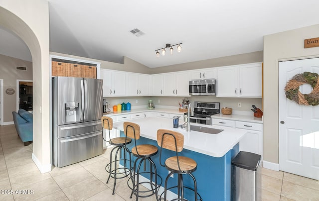 kitchen featuring light tile patterned floors, arched walkways, visible vents, stainless steel appliances, and light countertops