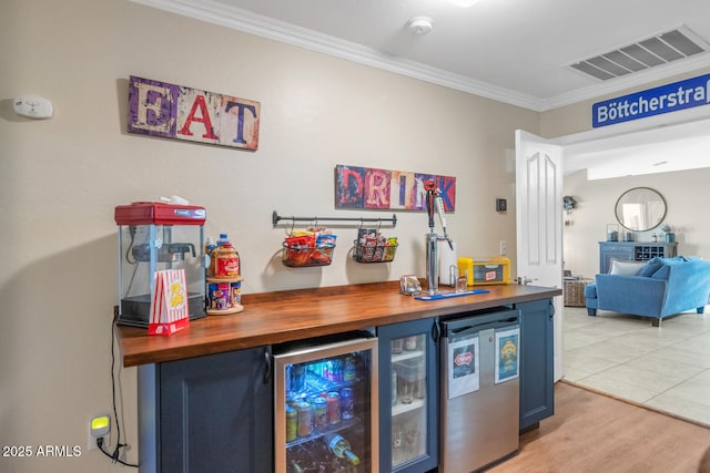 bar featuring visible vents, wine cooler, crown molding, a bar, and fridge