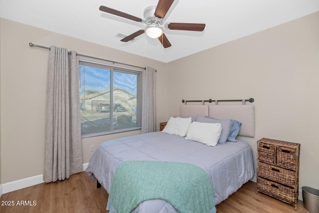 bedroom featuring a ceiling fan, visible vents, baseboards, and wood finished floors