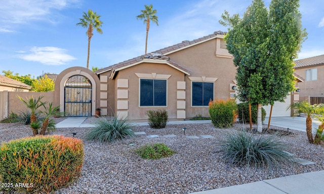 view of front of property featuring stucco siding, an attached garage, a gate, fence, and a tiled roof