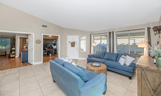 living area with lofted ceiling, light tile patterned floors, visible vents, and baseboards