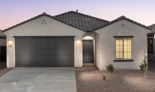 mediterranean / spanish home with a garage, stucco siding, driveway, and a tiled roof