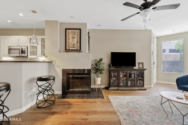 3633 N 3rd Ave Unit 1035, Phoenix, AZ 85013 - living room with wood finished floors, a ceiling fan, a tile fireplace, recessed lighting, and baseboards