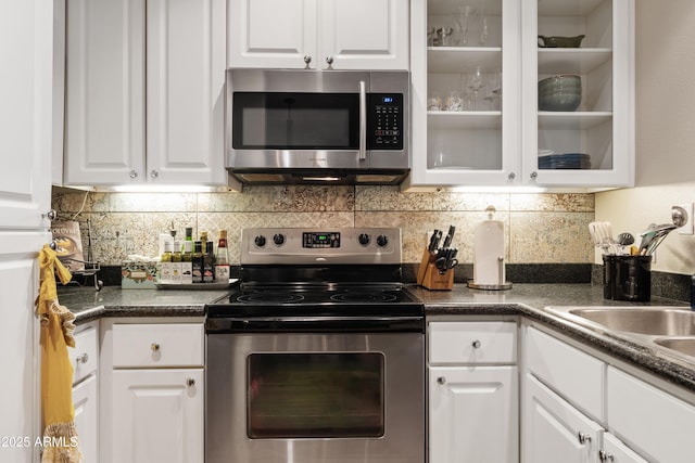 3633 N 3rd Ave Unit 1035, Phoenix, AZ 85013 - kitchen with appliances with stainless steel finishes, white cabinets, tasteful backsplash, glass insert cabinets, and dark countertops
