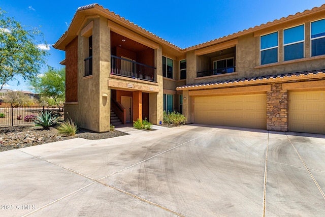 view of front of property featuring a garage, fence, driveway, a balcony, and stairway