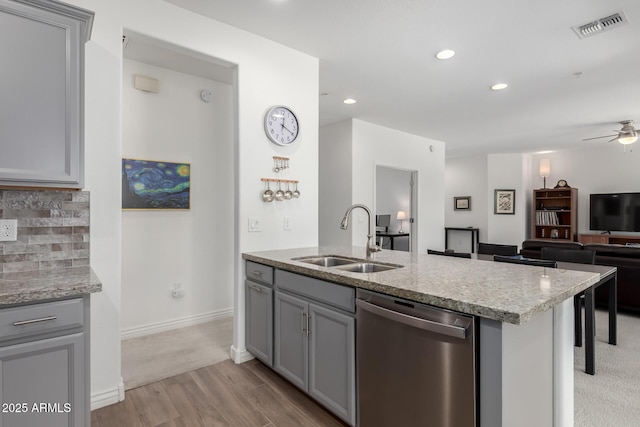 kitchen with stainless steel dishwasher, a sink, gray cabinets, light wood-style flooring, and recessed lighting