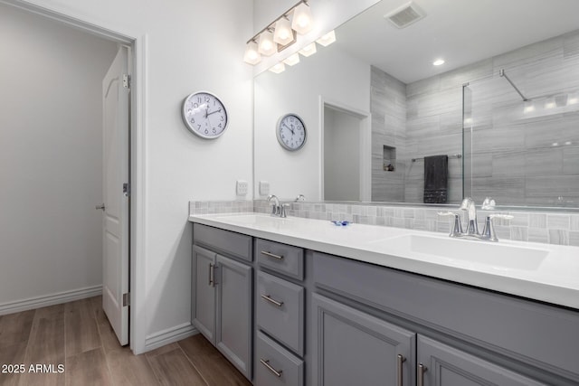full bathroom with walk in shower, decorative backsplash, double vanity, wood finished floors, and baseboards
