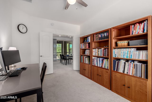 carpeted office with a ceiling fan